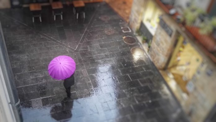 Persona sota un paraigües rosa a la Bisbal d'Empordà ruixat xafec