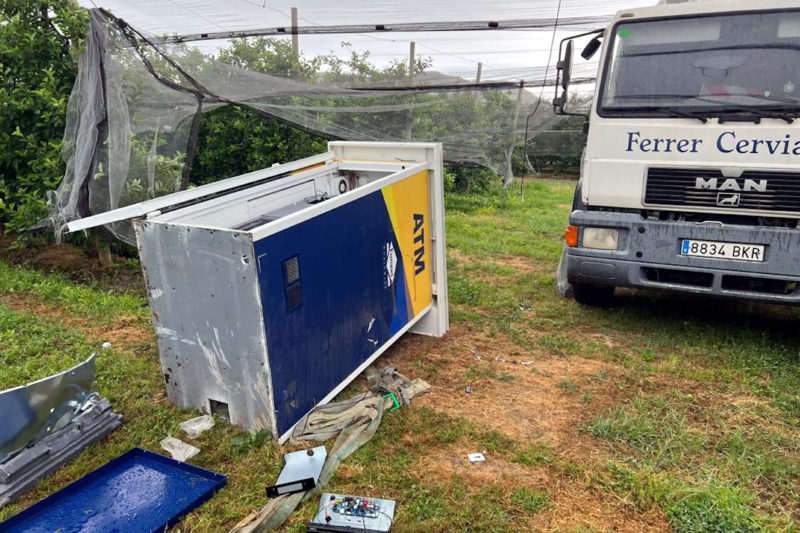 En primer terme, el caixer desmuntat a peces; al fons, el camió robat que els lladres han abandonat al camp de pomeres de Torroella de Montgrí - Cedida a l'ACN