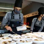Dos cuiners preparant diferents plats al restaurant Bo.TiC de Corçà – Imatge de Gerard Escaich Folch