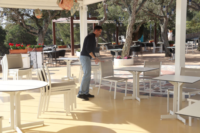 Un treballador de l'hotel Sant Roc de Calella de Palafrugell prepara la terrassa pels visitants d'aquesta Setmana Santa - Imatge de l'ACN/Aleix Freixas